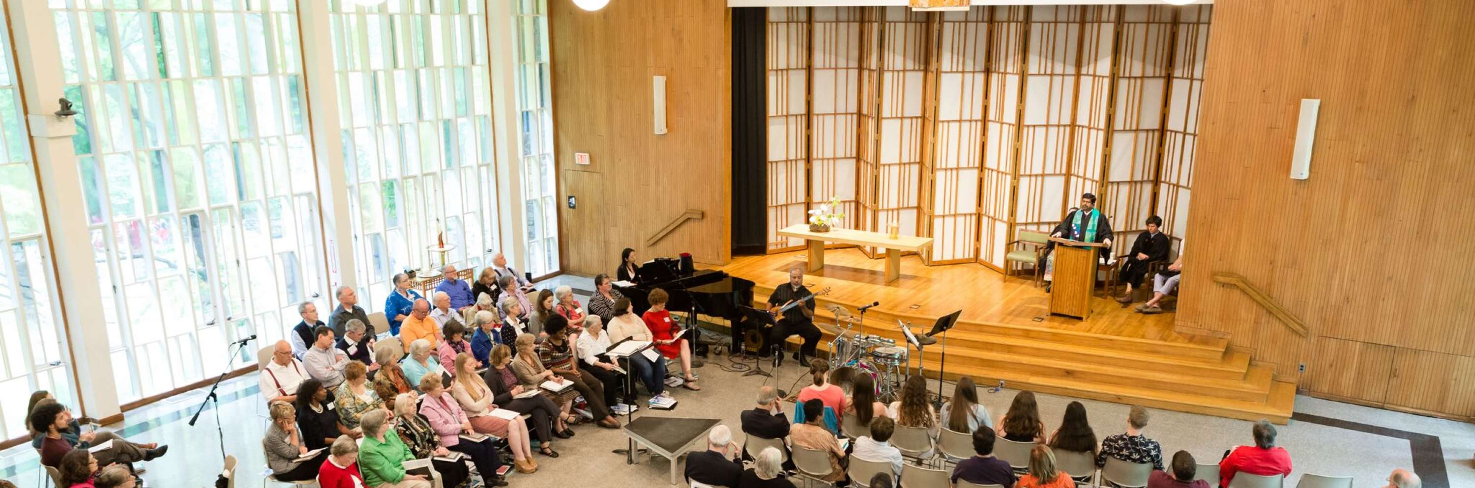 photo from the balcony of audience and stage during a Sunday worship service with Rev. Abhi speaking