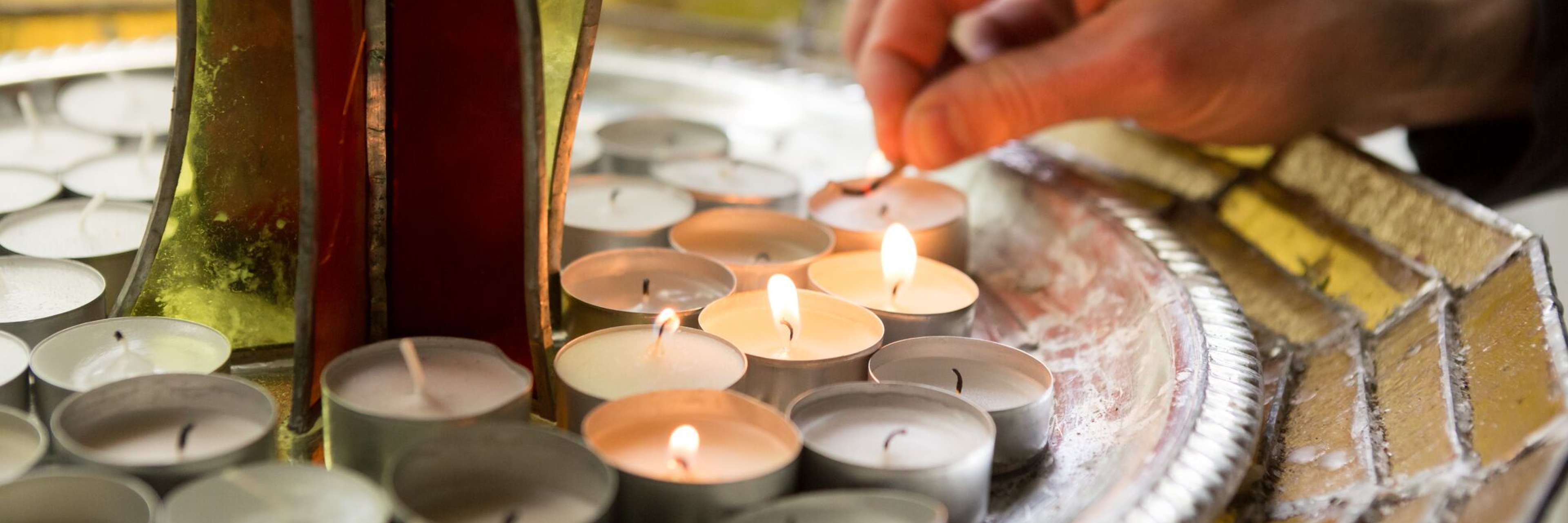 hand lighting a candle by the large Chalice in the Sanctuary at Cedar Lane